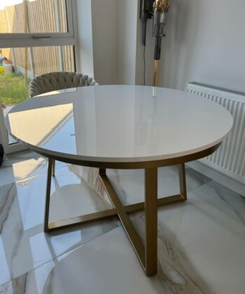 Aurora Gold Round Table with a sleek white top and gold metal base, positioned in a modern interior setting, emphasizing luxury and style for contemporary home decor.