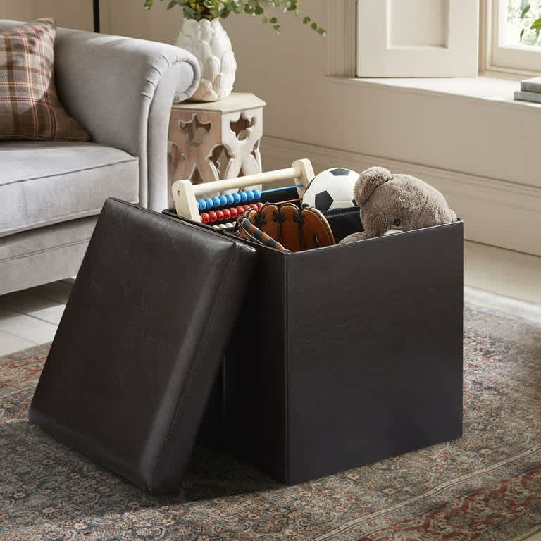 Dark brown leather storage ottoman used as a footstool and storage solution in a cozy living room