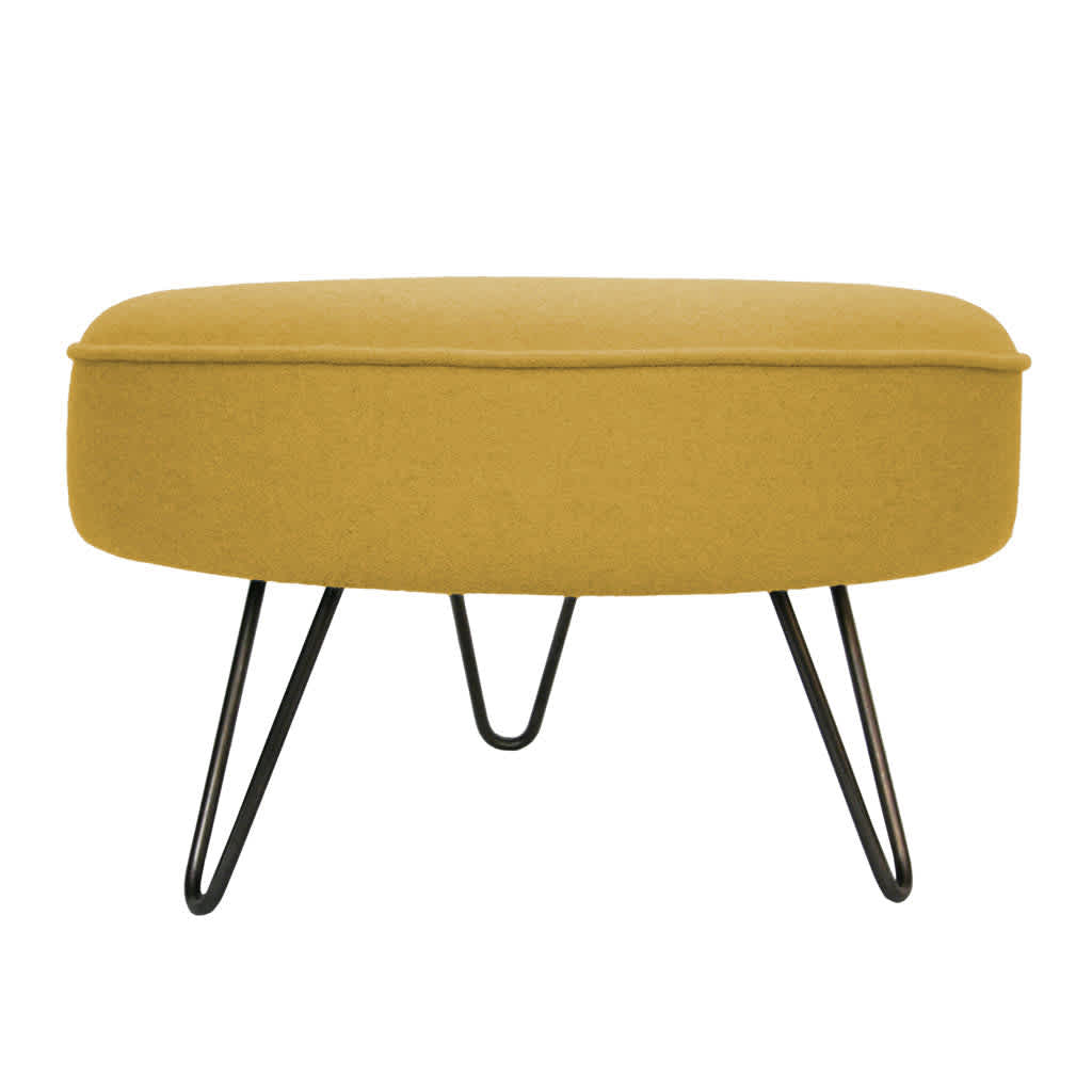 Modern handcrafted footstool with mustard-yellow cushion and black hairpin legs, exemplifying stylish comfort and elegance