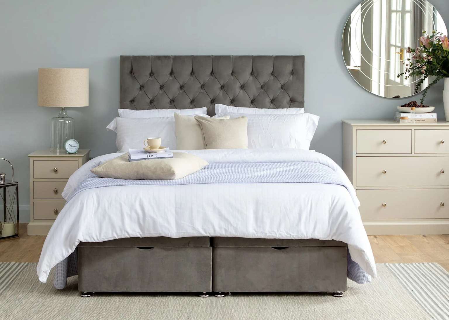 Grey velour velvet tufted headboard on a neatly made bed in a softly decorated bedroom