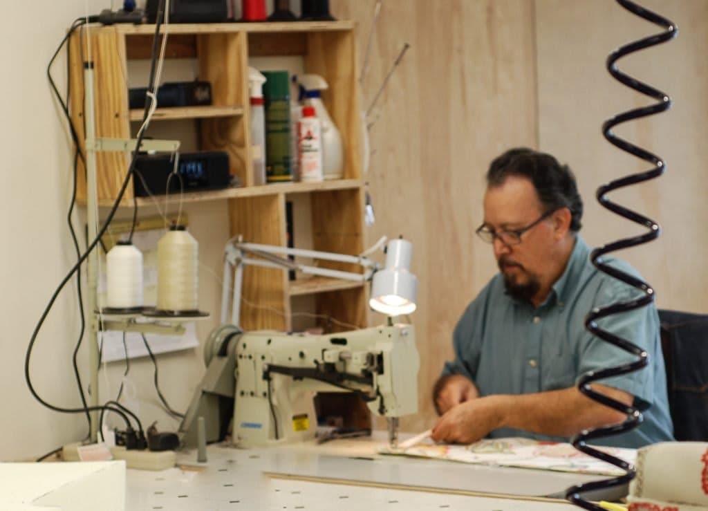 Craftsman handcrafting furniture upholstery in a workshop, illustrating the artisanal process behind handcrafted footstools