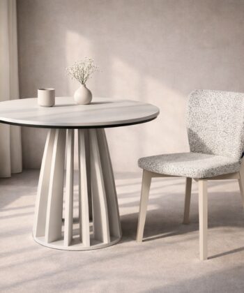 Modern white round table with vase and chair in minimalist interior setting.