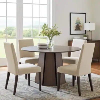 Round dining table with four upholstered chairs in a bright, modern room.