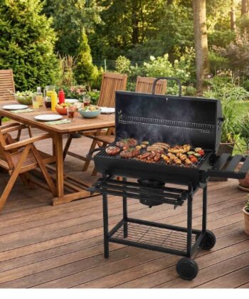 BBQ grill on a wooden patio with outdoor dining table and garden in the background.