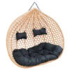 Egg-shaped hanging rattan chair with black cushions and pillows, perfect for outdoor or indoor relax.