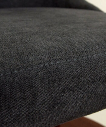 Black fabric upholstered pouffe with a textured surface, close-up view.