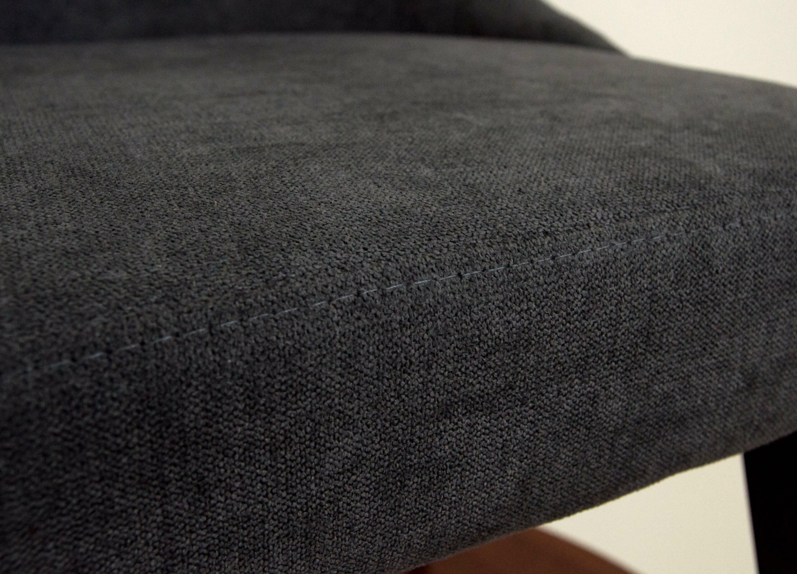 Black fabric upholstered pouffe with a textured surface, close-up view.