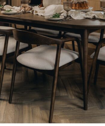 Modern dark wood dining chairs with light fabric seats around a wooden table.