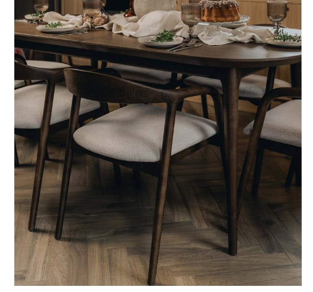 Modern dark wood dining chairs with light fabric seats around a wooden table.