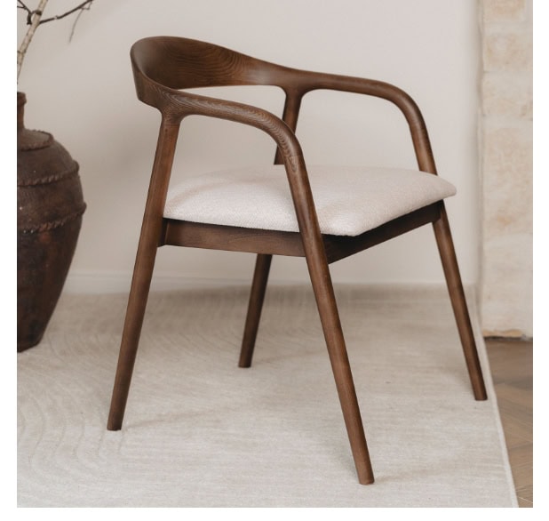 Modern wooden armchair with beige cushion in stylish interior setting.