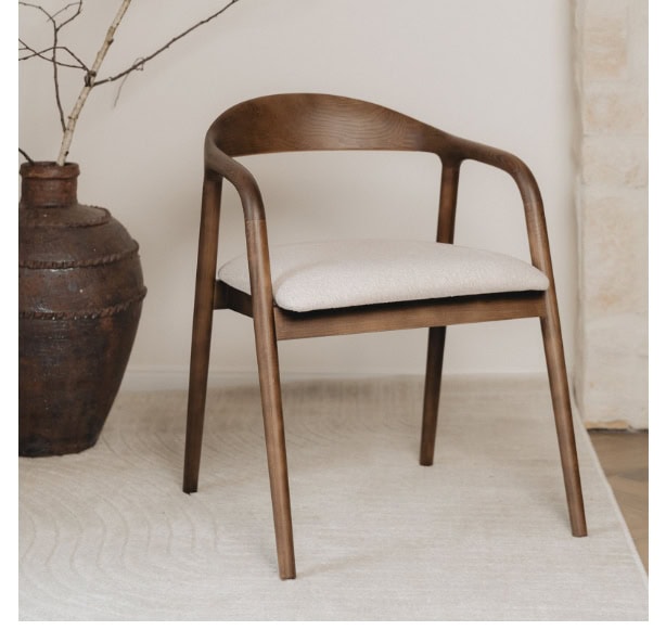 Modern wooden chair with beige cushion in minimalist interior setting.