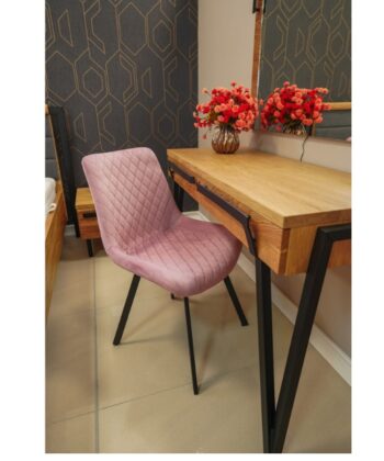 Soft pink quilted chair at a wooden desk with floral decor in a modern interior setting.