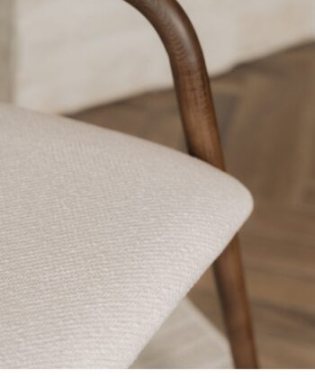 Soft beige upholstered pouffe with wooden legs, ideal for modern living room decor.