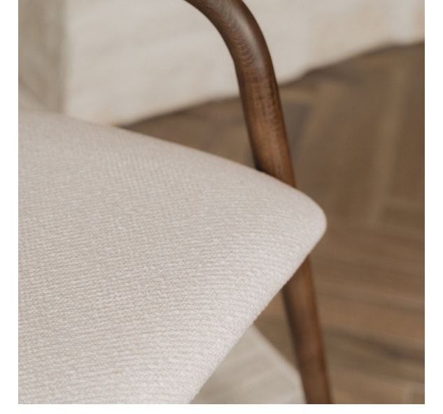 Soft beige upholstered pouffe with wooden legs, ideal for modern living room decor.