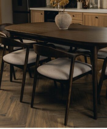 Soft-close wooden dining table with black chairs in a modern kitchen setting.