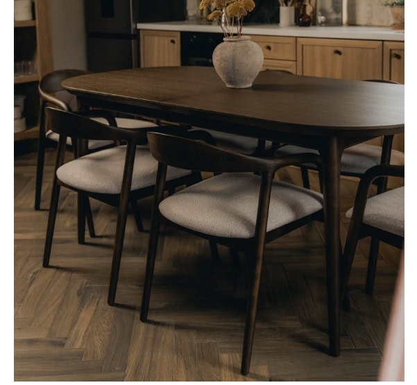 Soft-close wooden dining table with black chairs in a modern kitchen setting.