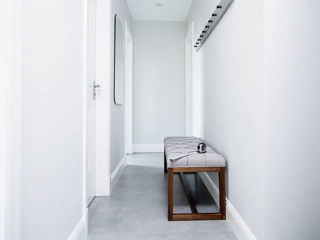 Oversized bench crowding a narrow hallway walkway near a swinging door